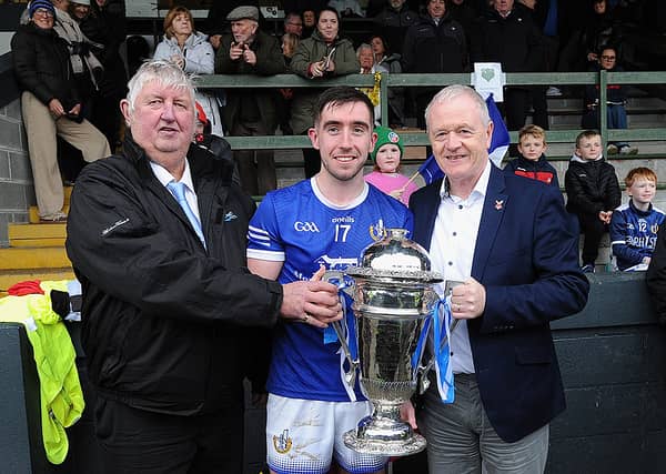 Naomh Máirtín captain Eoghan Callaghan is presented with the Joe Ward Cup by Seamus Keenan of sponsor Anchor Tours (left) and Seán McClean of LCB (right). Photo by Arthur Kinahan