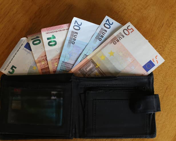 Euro notes sit inside a wallet