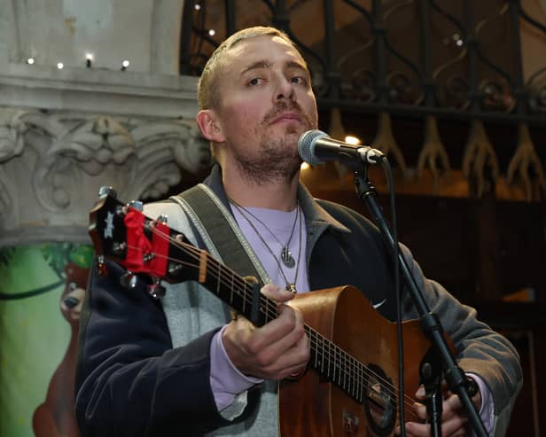 Dermot Kennedy holding a guitar and singing