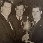 Dickie Kieran is presented with the Macardle Cup by County Board chairman, Seán Murray, with in centre, Nick Mackin. St Kevin's won the trophy three years in succession in the 1960s