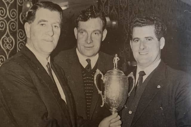Dickie Kieran is presented with the Macardle Cup by County Board chairman, Seán Murray, with in centre, Nick Mackin. St Kevin's won the trophy three years in succession in the 1960s