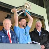 Newtown Blues captain, Ciarán Downey, lifts the Joe Ward Cup, with Seán McClean (LCB chairman) (left) Seamus Keenan (sponsor Anchor Tours)