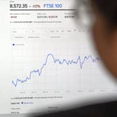 A man looks at the FTSE 100 on a screen